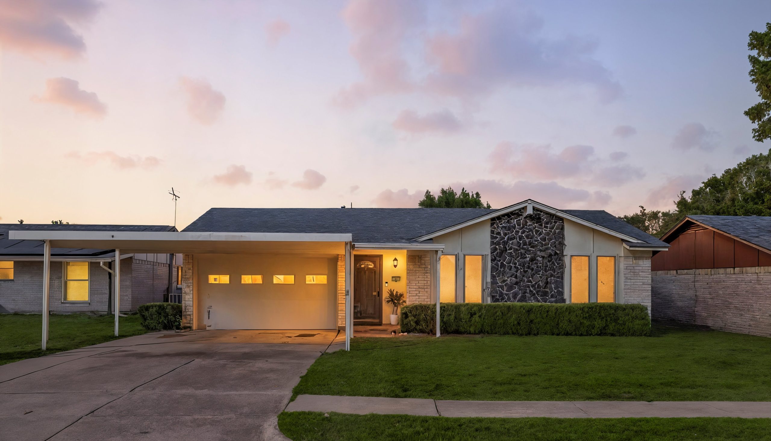 Front exterior of 1801 Homestead Place in Garland, TX — single-story traditional home with stone accent wall, carport, and well-kept lawn at sunset.